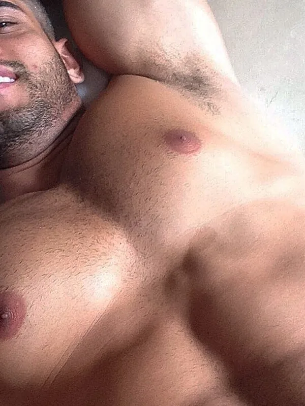 Homme torse nu allongé, regardant l'objectif, avec barbe et cheveux courts.
