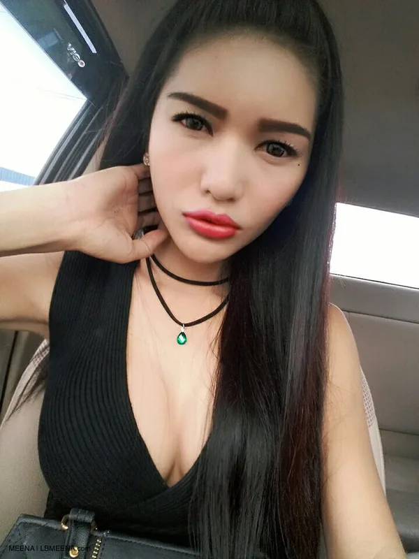 Portrait d'une femme aux cheveux noirs longs, maquillée, portant un haut noir et un collier, assise dans une voiture.