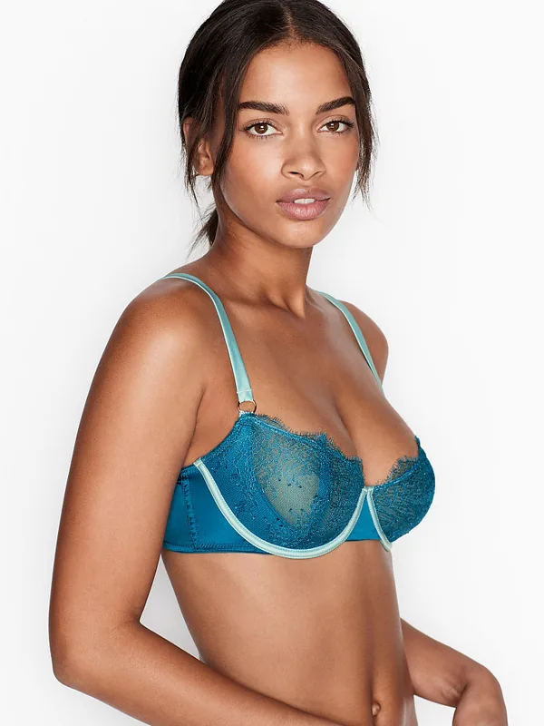 Femme portant un soutien-gorge bleu turquoise en dentelle, regardant l'objectif sur fond blanc.