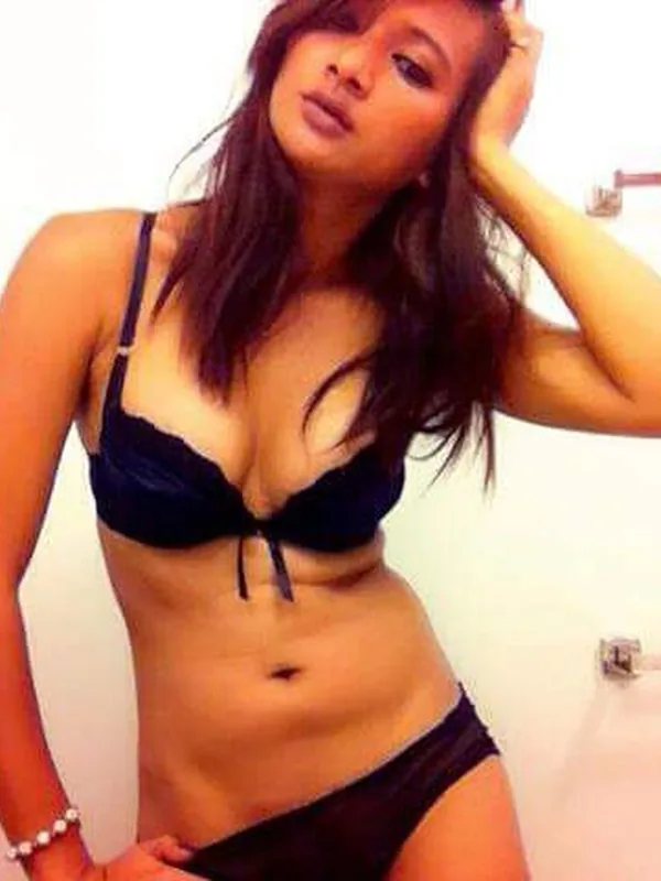 Femme en sous-vêtements noirs posant dans une salle de bain, regardant l'objectif.